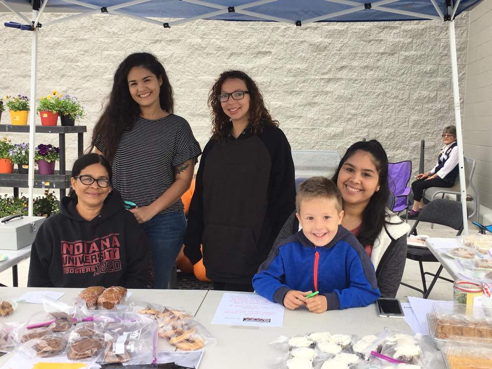 Employees with kids under tent for bake sale