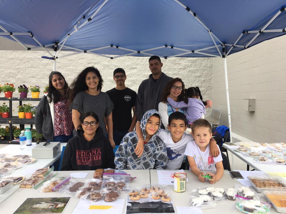 Employees with kids under tent for bake sale
